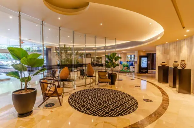 Interior del InterContinental Medellín con mármol, vegetación y una iluminación cálida